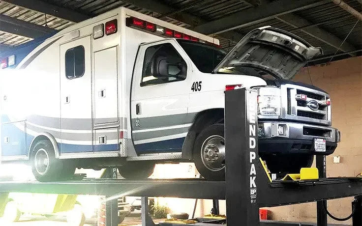 BendPak HDS-18E 18,000 lb. 4 Post Heavy Duty Lift with an ambulance lifted to maximum height- Mechanic Super Store