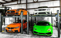 image of two BendPak HD-9XL 9,000 lb. 4 Post Storage Lifts inside a garage holding a total of 4 vehicles with the bendpak car lift logo - Mechanic Super Store faceing forward.