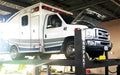BendPak HDS-18E 18,000 lb. 4 Post Heavy Duty Lift with an ambulance lifted to maximum height- Mechanic Super Store