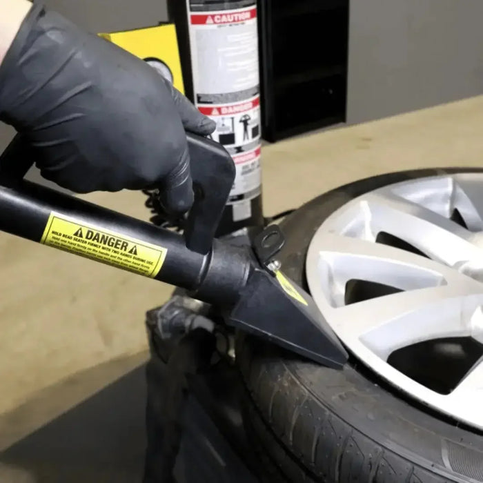 Up close image of the Ranger R980DP-L Tire Changer Swing Arm Dual-Tower Assist machine with a rim being removed from a damaged tire- Mechanic Super Store