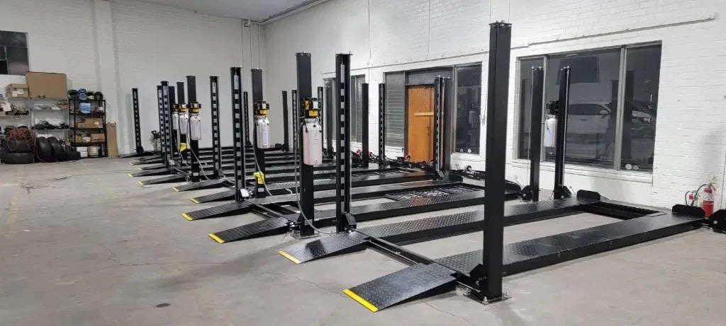 Tuxedo/Valor VP8K-DX 8,000 lb 4 Post Deluxe Storage Lift - 5 of them arranged pleasantly in a line in a warehouse.
